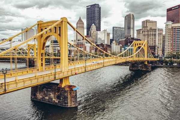 A photo of a yellow bridge crossing the river into downtown Pittsburgh