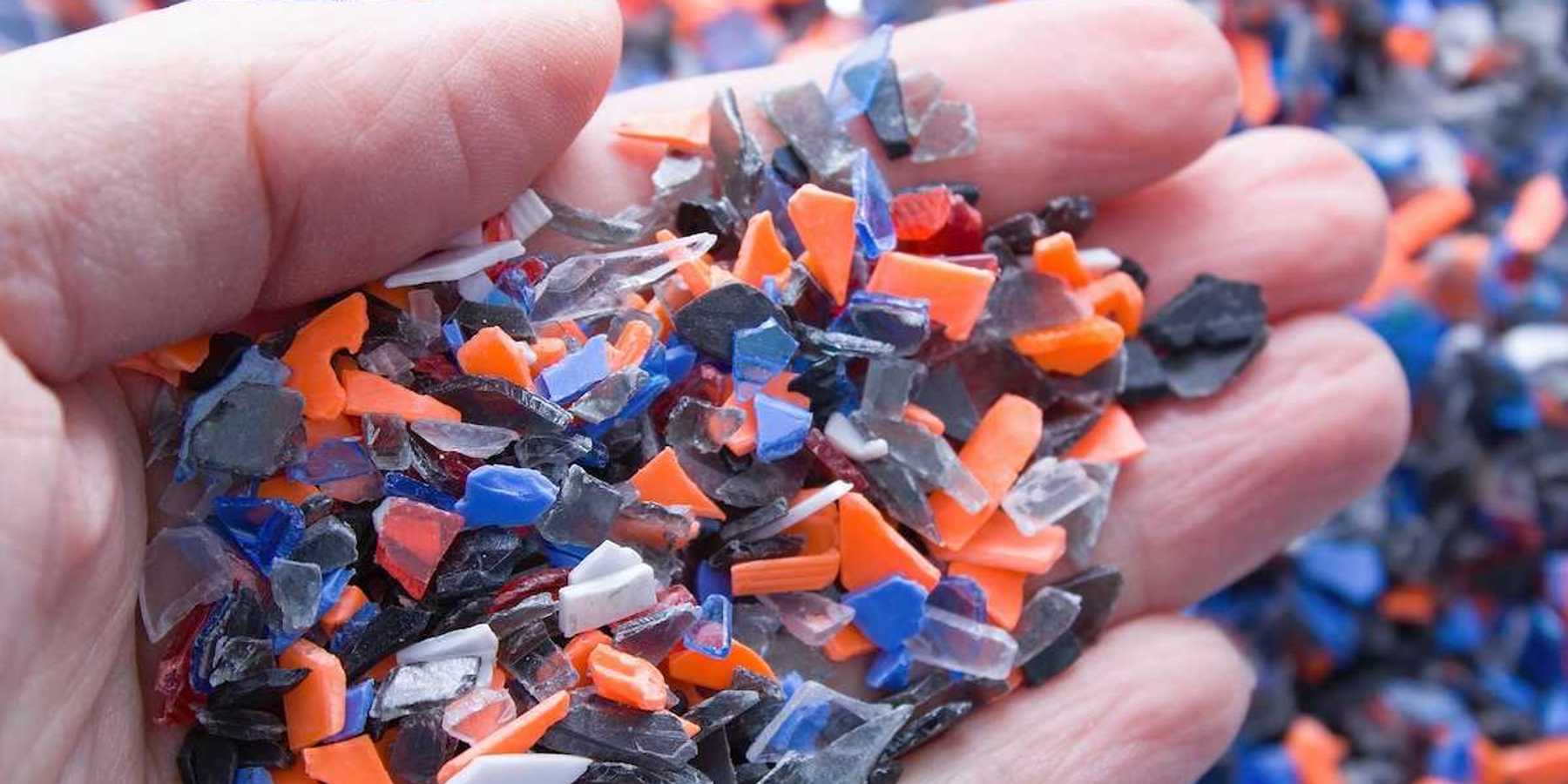 A pile of microplastics - small pieces of hard plastic on palm, intended for further processing.