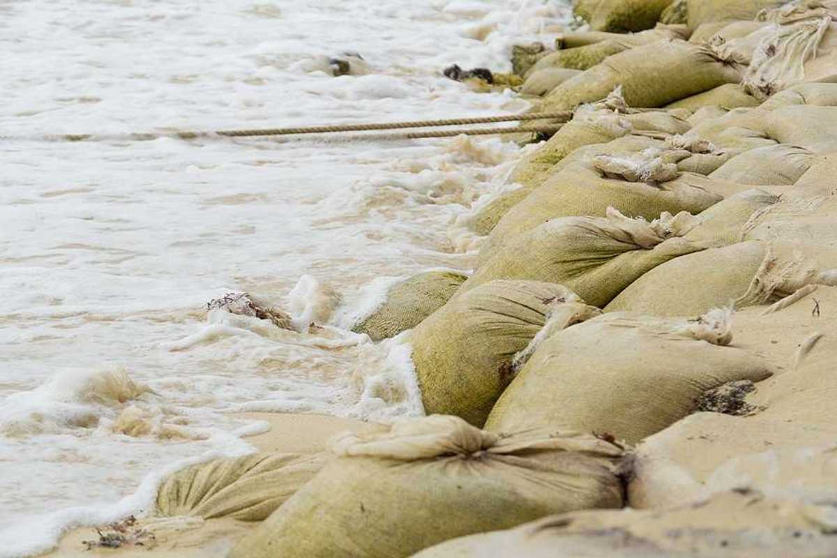 A pile of sandbags helping to keep waves from flooding the beach