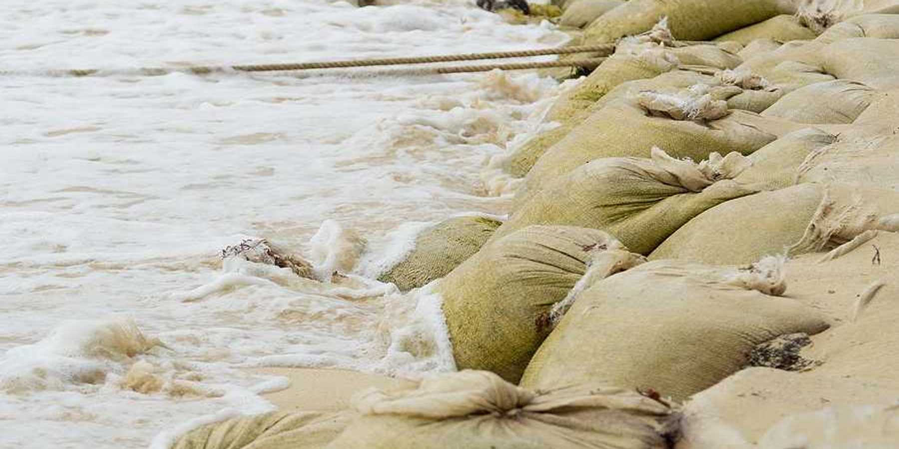 A pile of sandbags helping to keep waves from flooding the beach