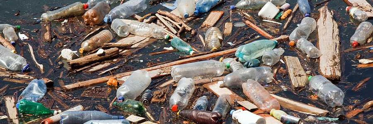 A pile of trash, including plastic bottles, floating in a water source
