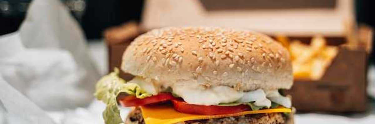 A plant-based burger on paper packaging with french fries in the background