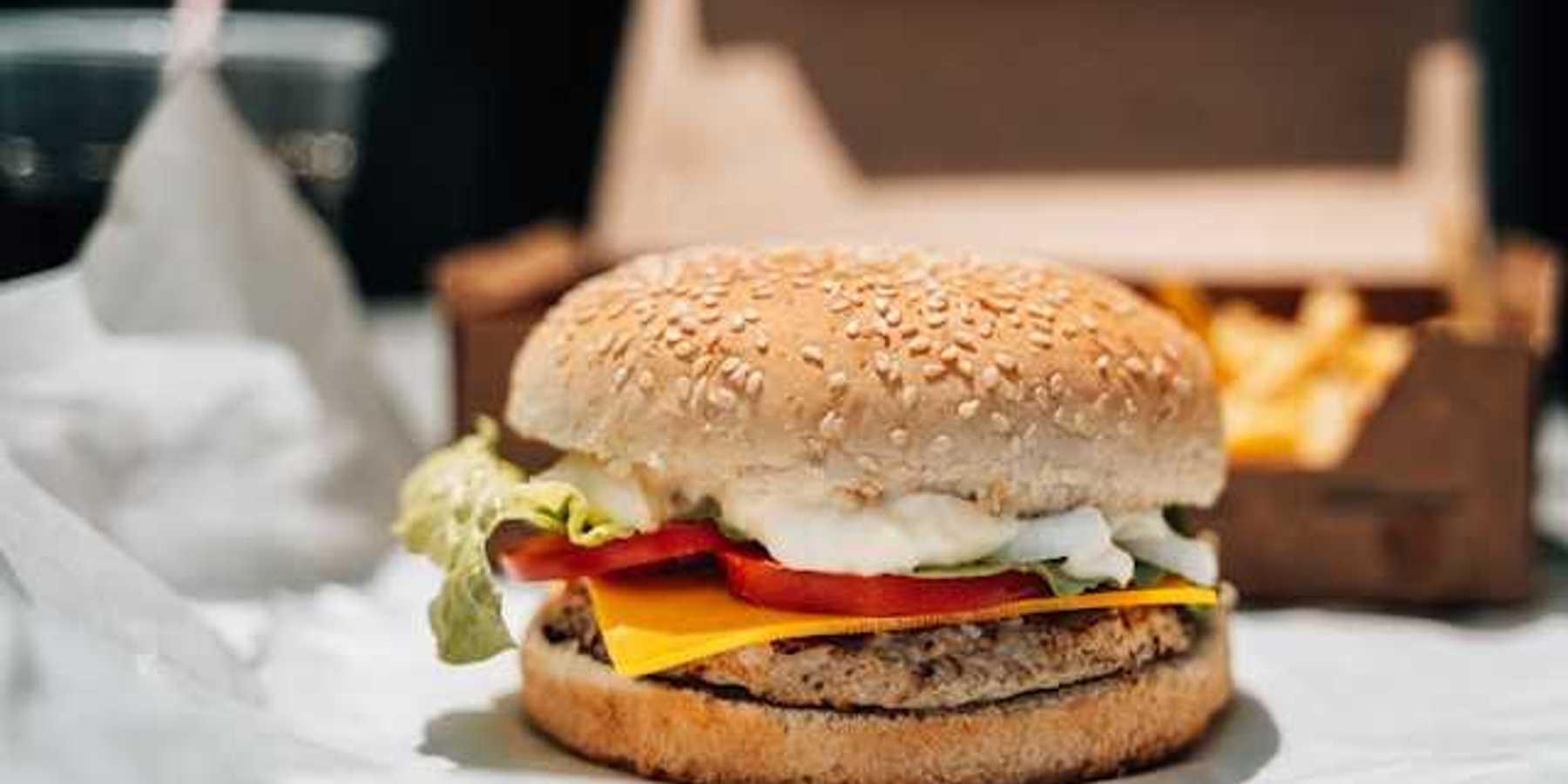 A plant-based burger on paper packaging with french fries in the background
