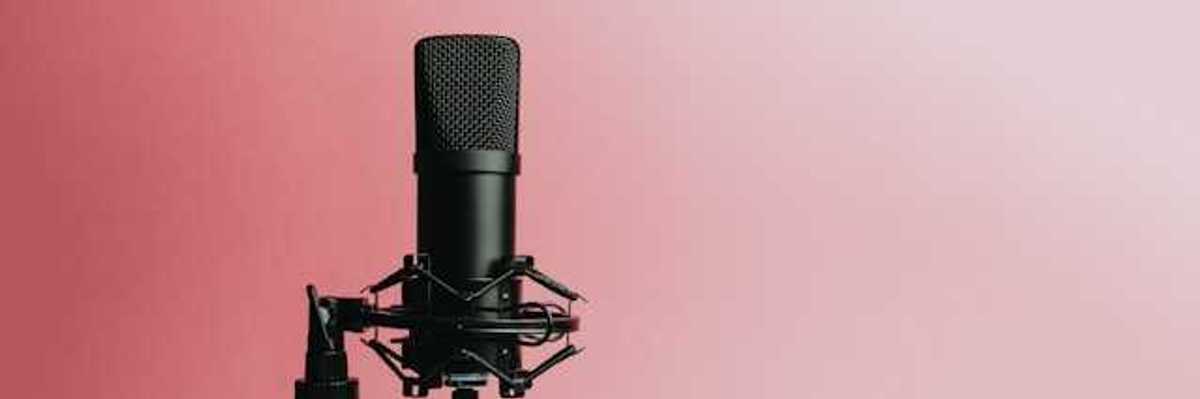 A podcast microphone against a pink background