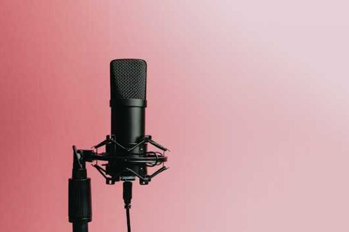 A podcast microphone against a pink background