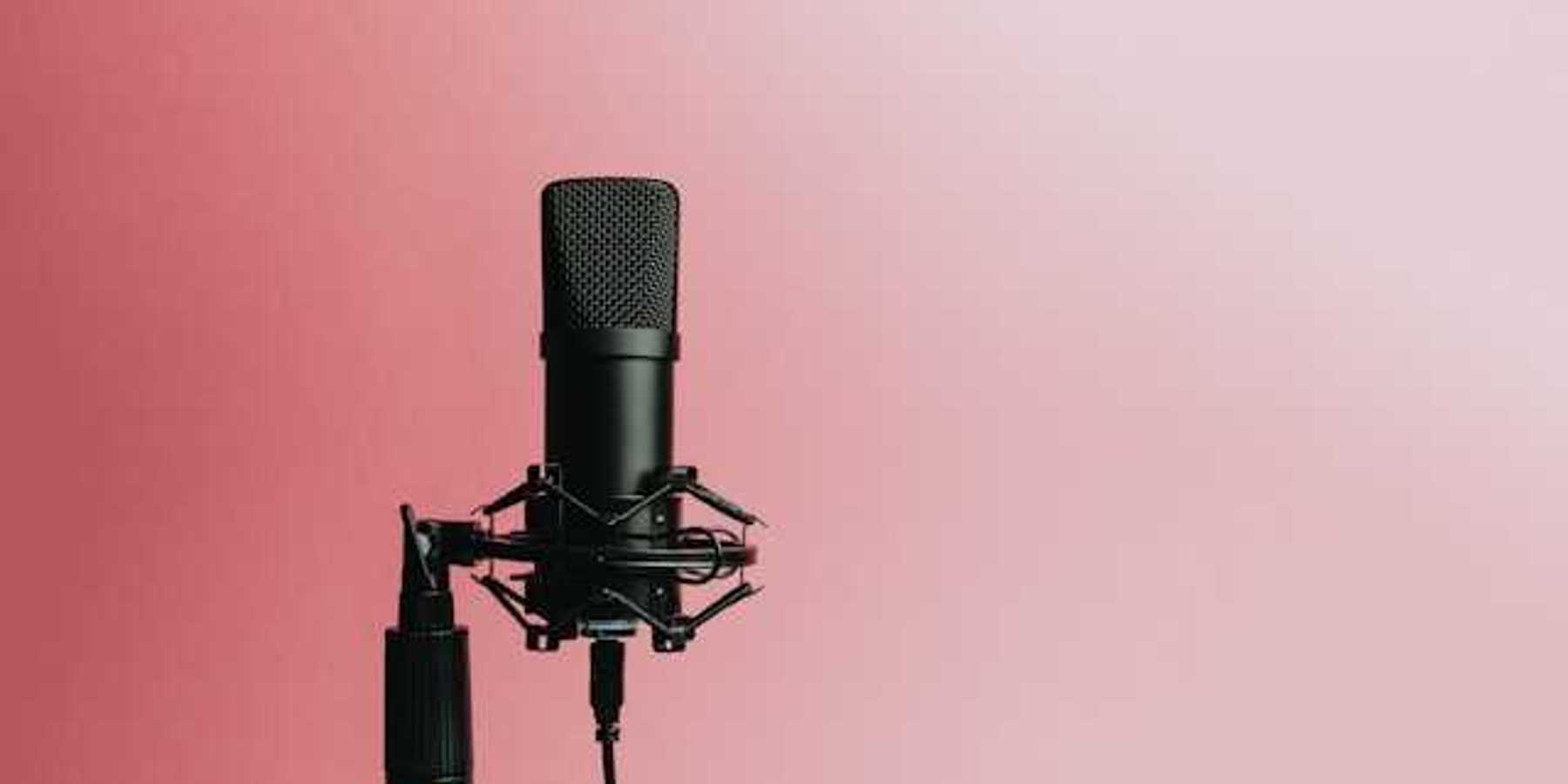 A podcast microphone against a pink background