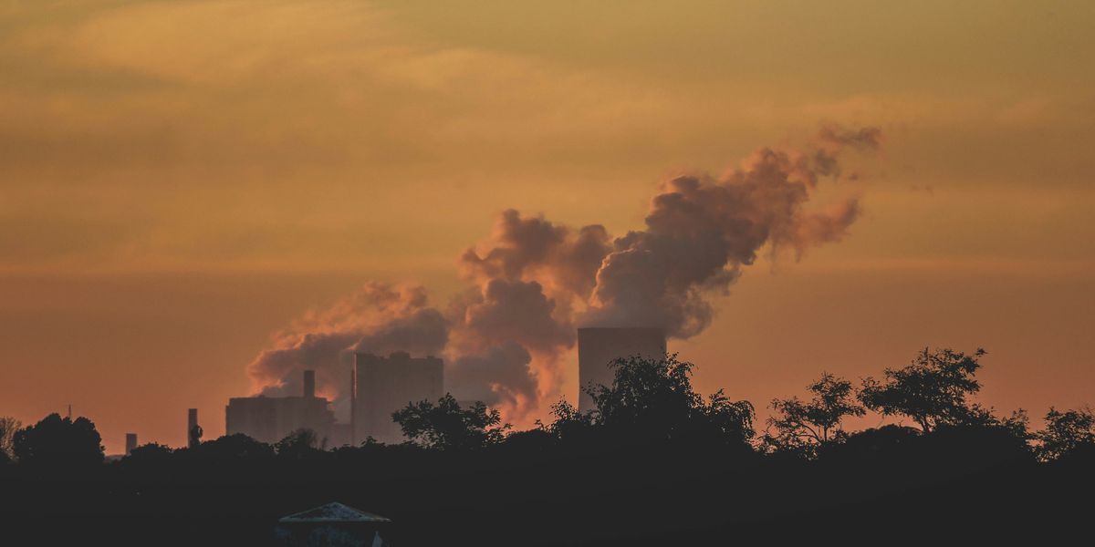 A power plant in the distance with smoke arising from towers