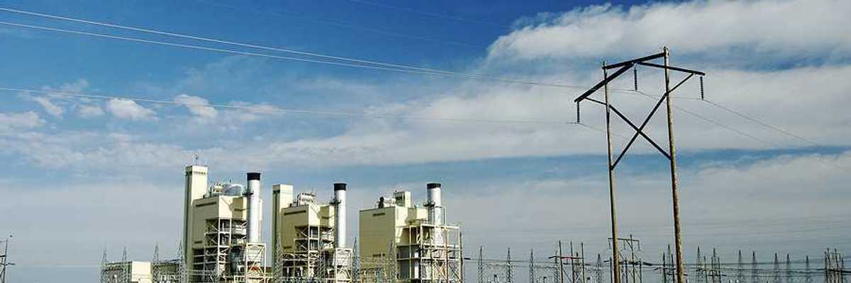 A power plant on a sunny day with a field in the foreground