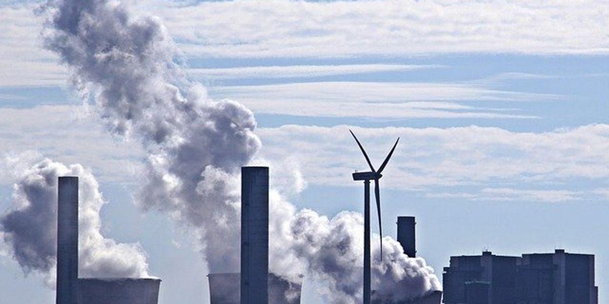 A power plant with a wind turbine in the foreground.