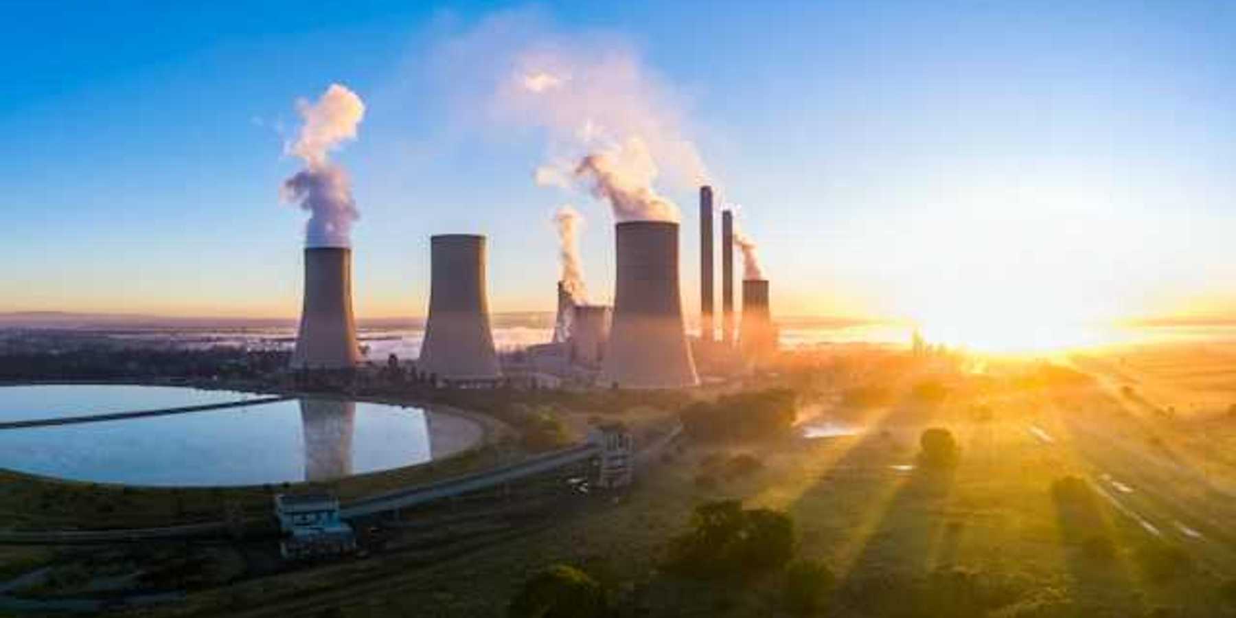 A power station with cooling towers seen at sunrise