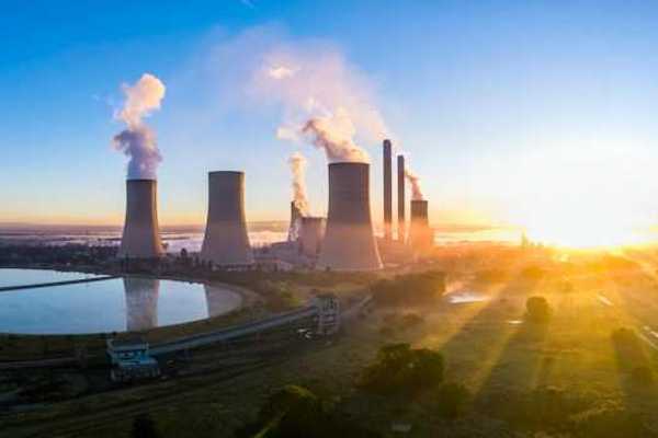 A power station with cooling towers seen at sunrise