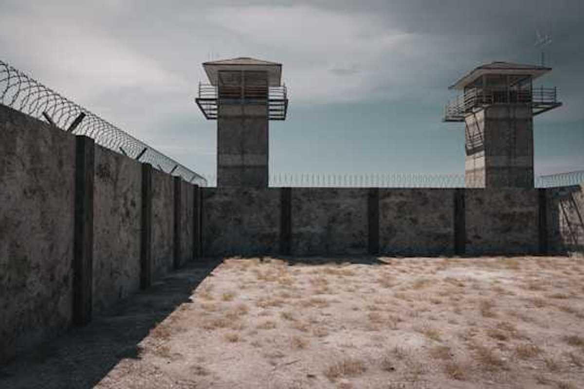 A prison wall with barbed wire and guard towers