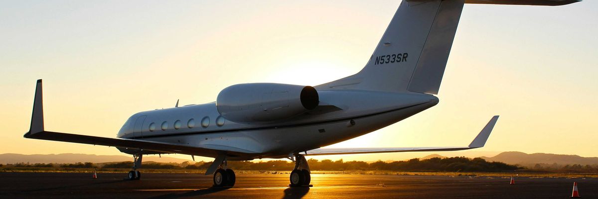 A private jet on the runway with the setting sun in the background