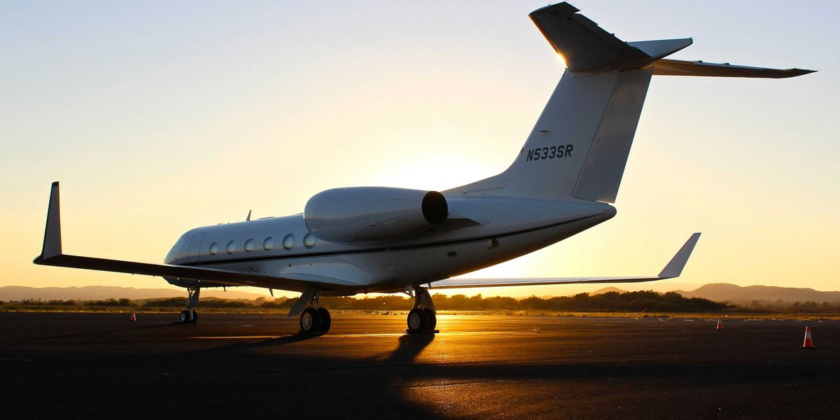 A private jet on the runway with the setting sun in the background