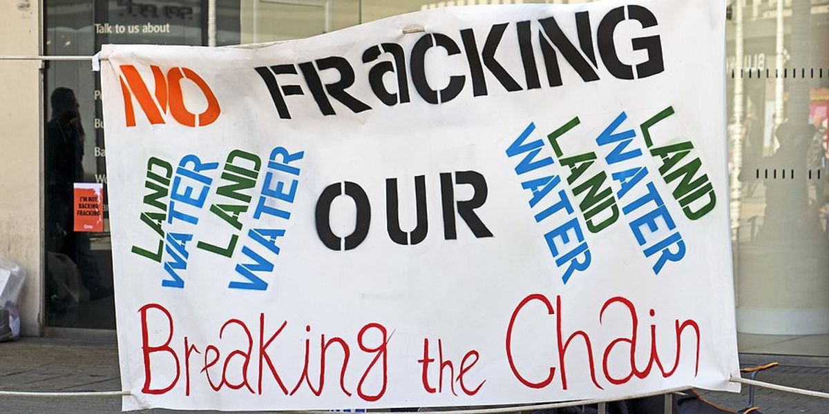 A protester with a sign saying No Fracking our Land and Water.