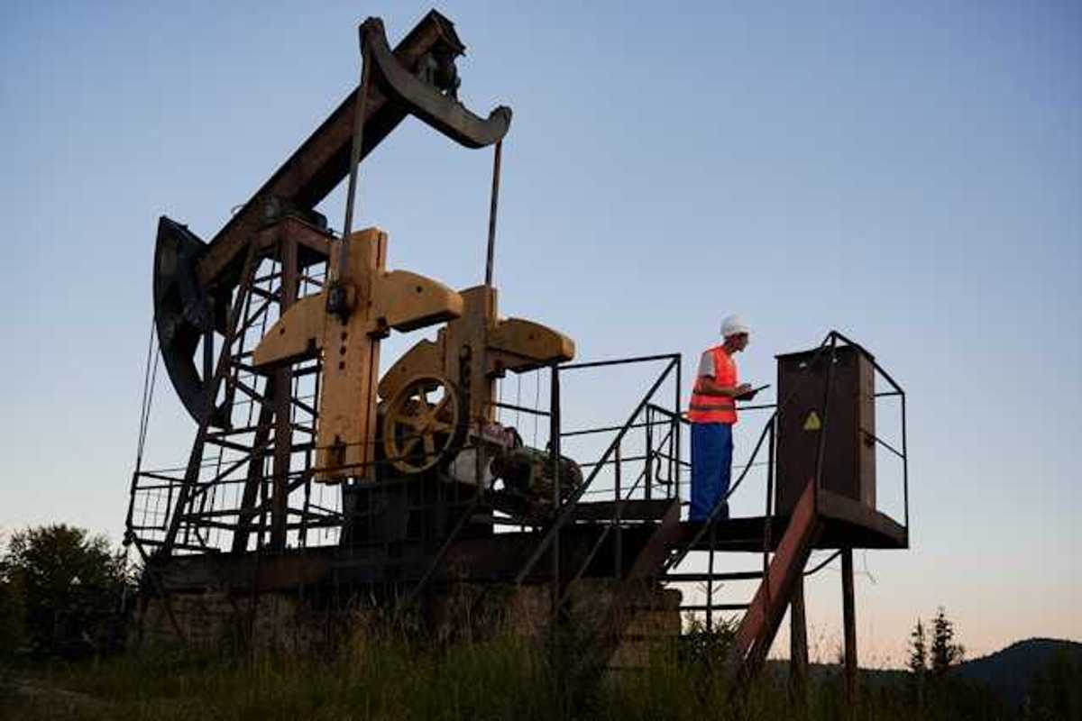 A pump jack with a maintenance worker on a platform next to it