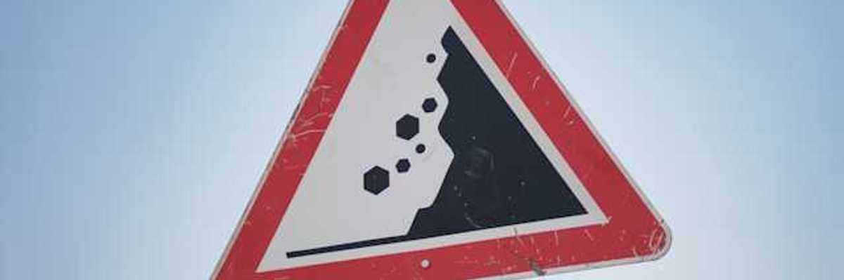 A red and black road sign warning of landslide danger
