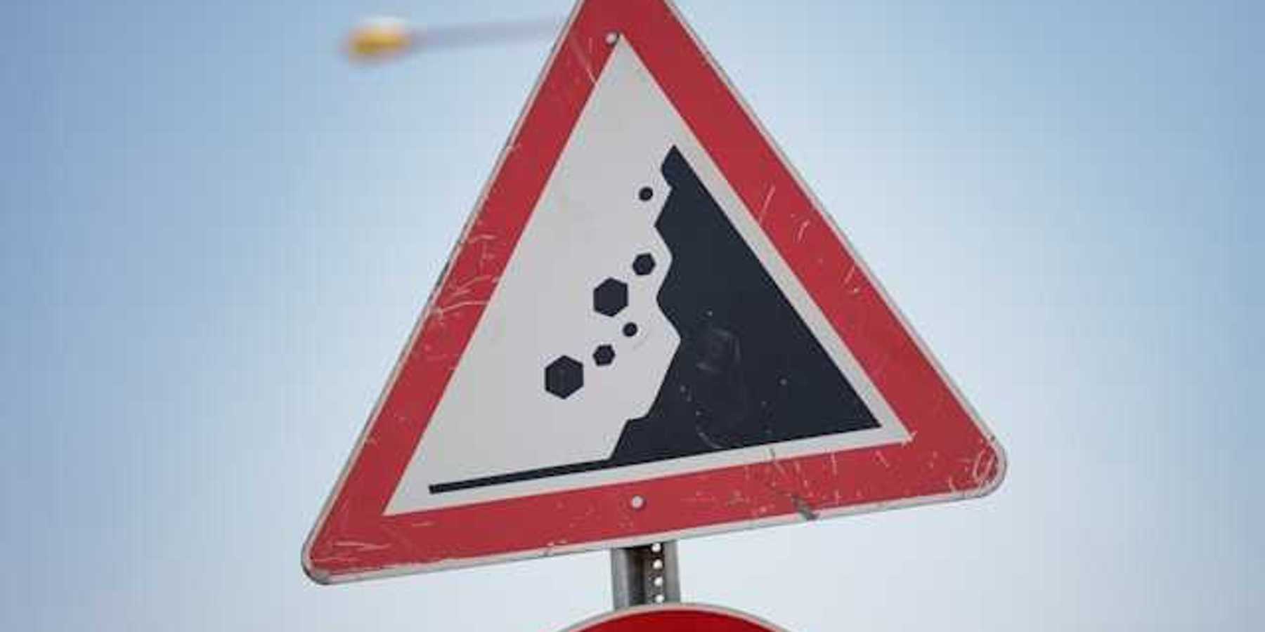 A red and black road sign warning of landslide danger