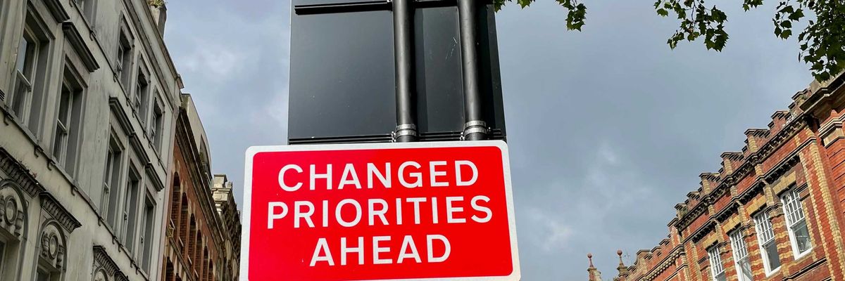 A red and white street sign saying Changed Priorities Ahead