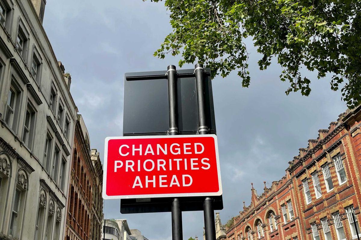 A red and white street sign saying Changed Priorities Ahead