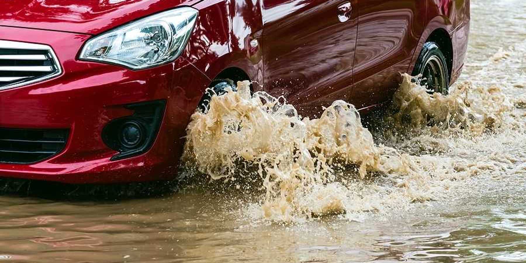 A red car driving through flood waters