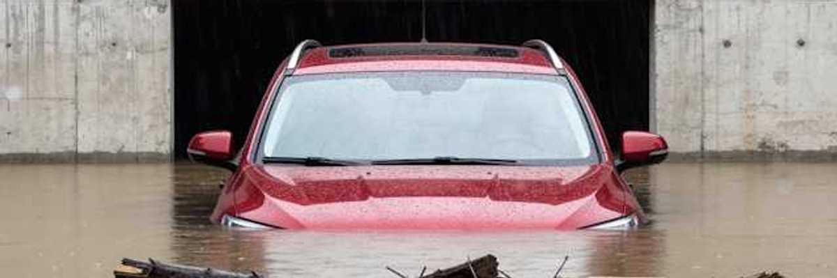 A red car submerged under flood waters