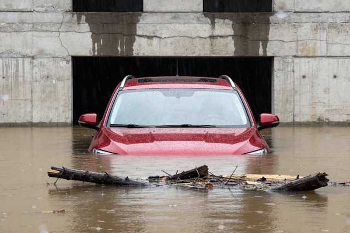 A red car submerged under flood waters