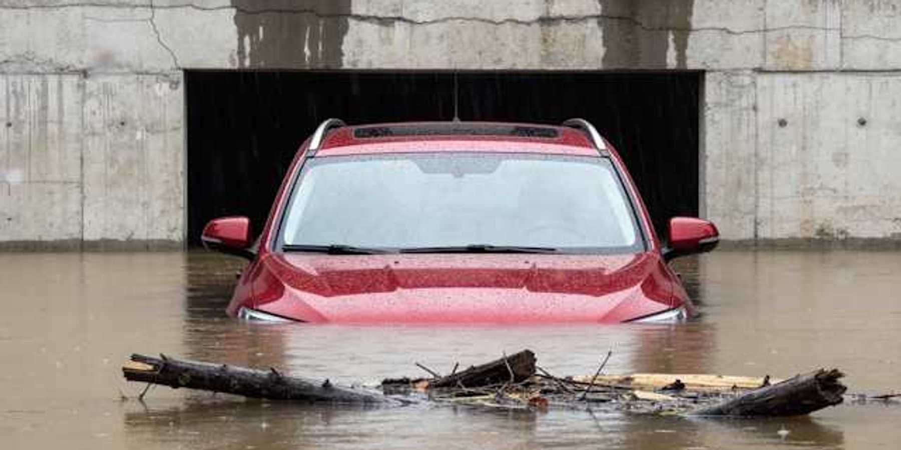 A red car submerged under flood waters
