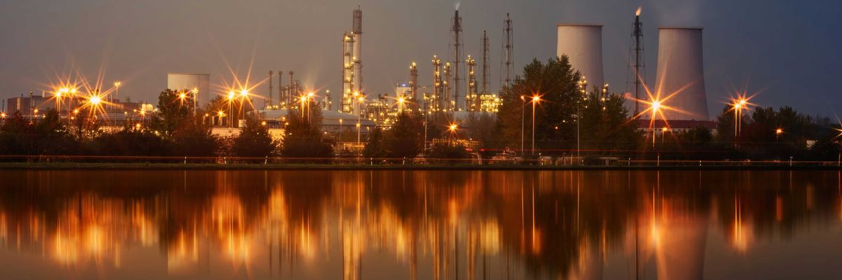 A refinery at night in front of a water source