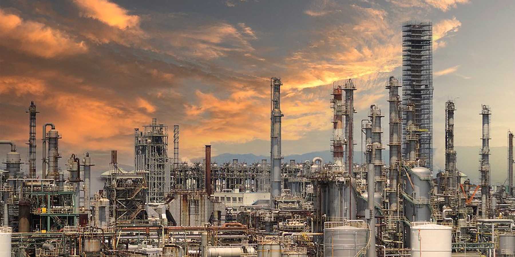 A refinery under a pink, cloud-strewn sky.