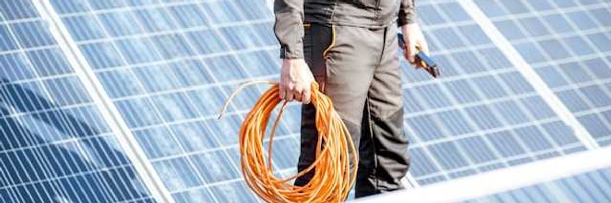 A renewable energy worker holding cable inspecting solar panels