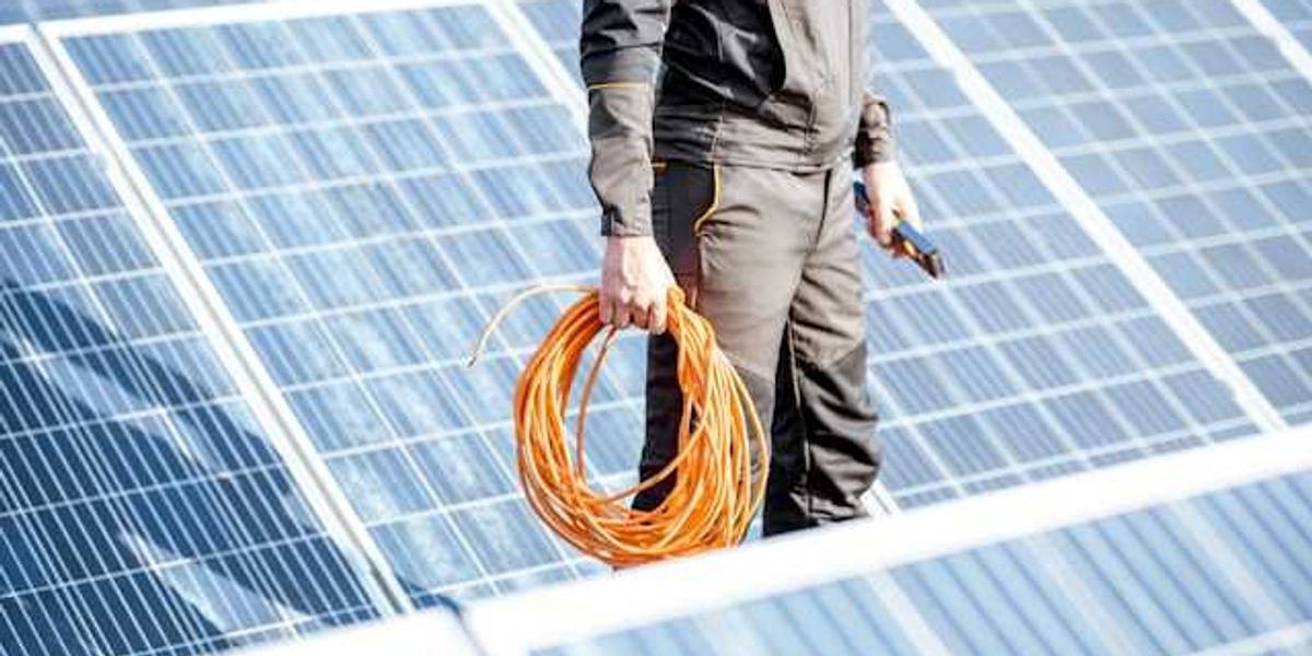 A renewable energy worker holding cable inspecting solar panels