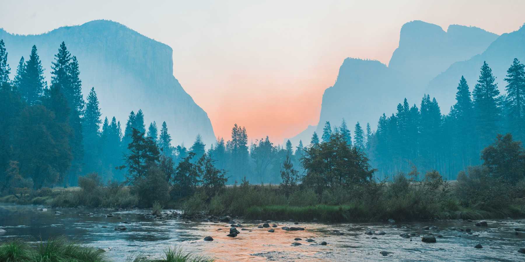 A river running through Yosemite park with half dome in the background.
