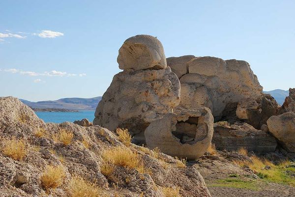 A rock formation in the desert with a lake in the background