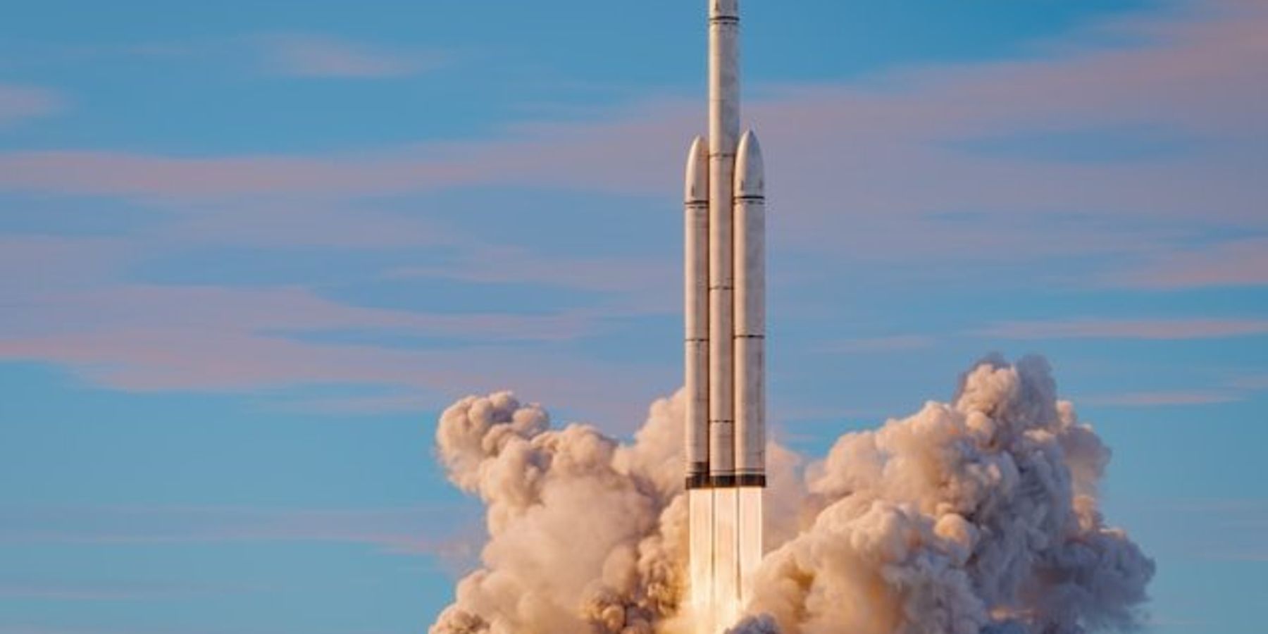 A rocket launch with a blue sky and clouds in the background