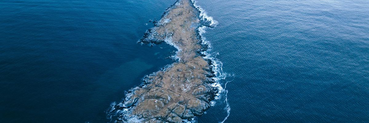 A rocky island in the middle of the ocean viewed from above