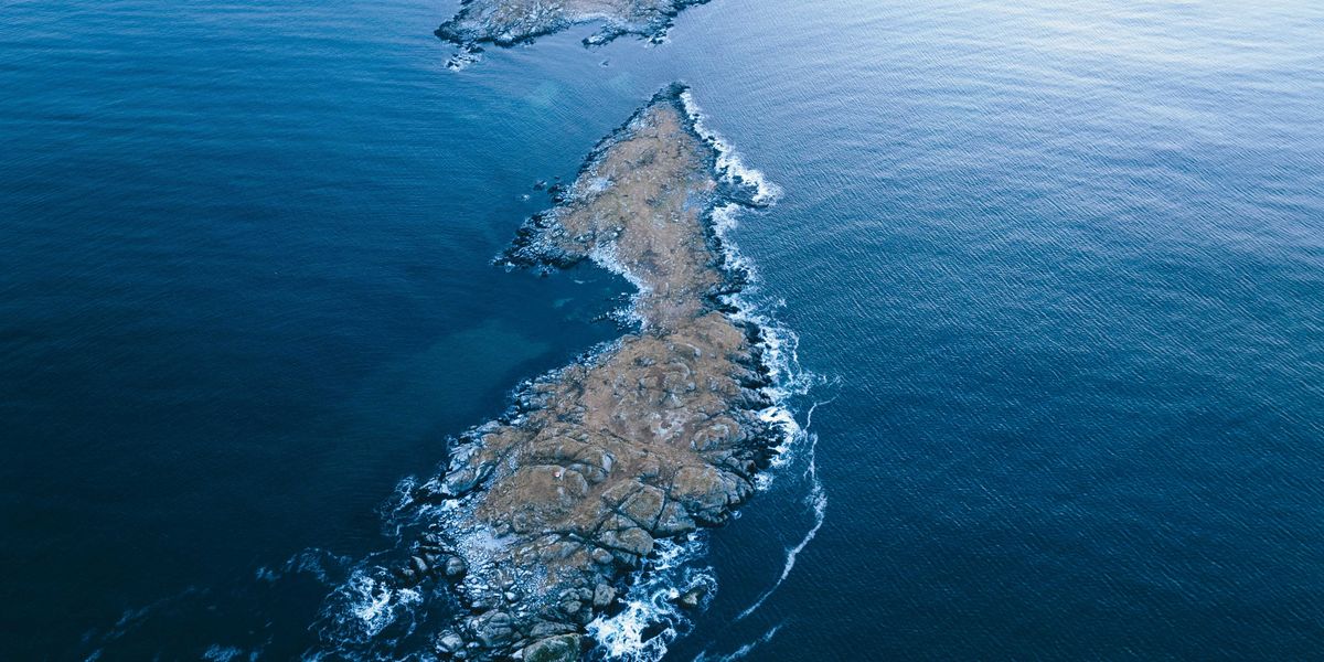 A rocky island in the middle of the ocean viewed from above