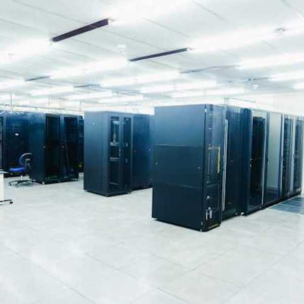 A room full of black server cabinets under fluorescent lighting