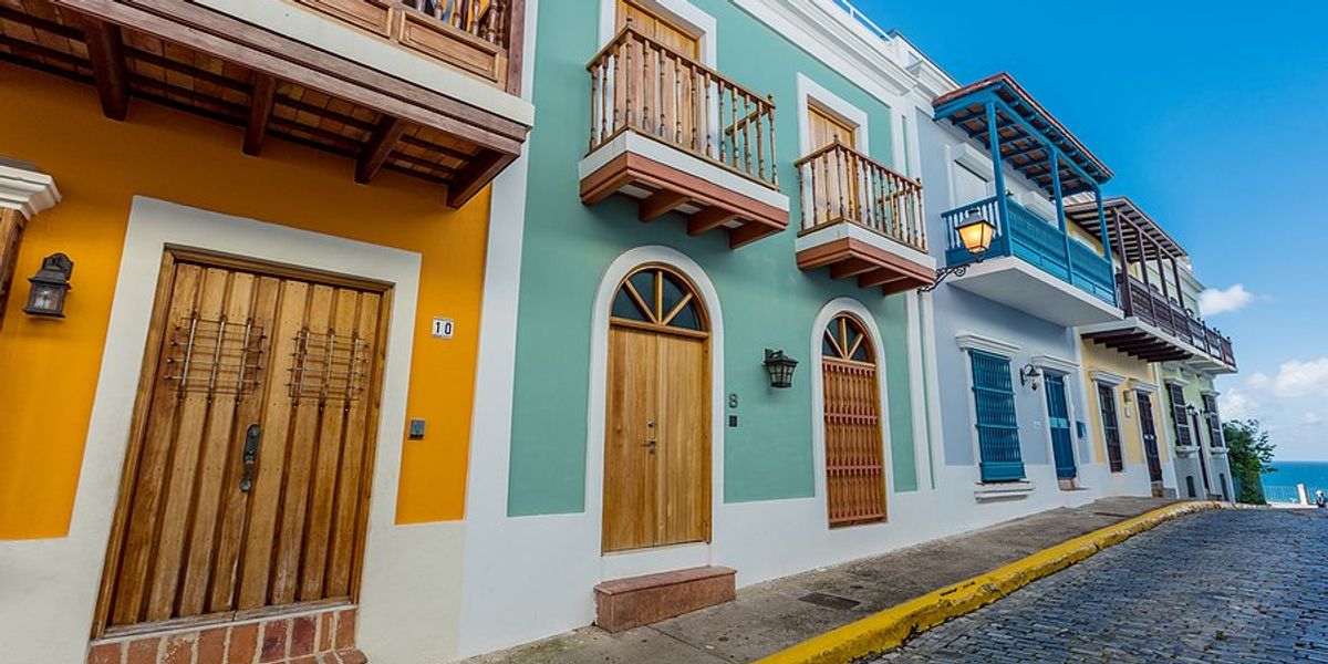 A row of brightly colored houses along a cobblestone street leading to the sea.