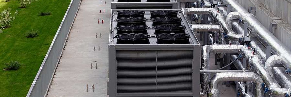 A row of data center cooling towers connected to a building with pipes