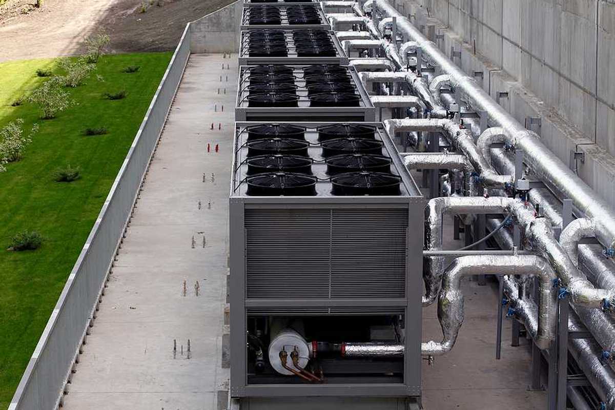 A row of data center cooling towers connected to a building with pipes