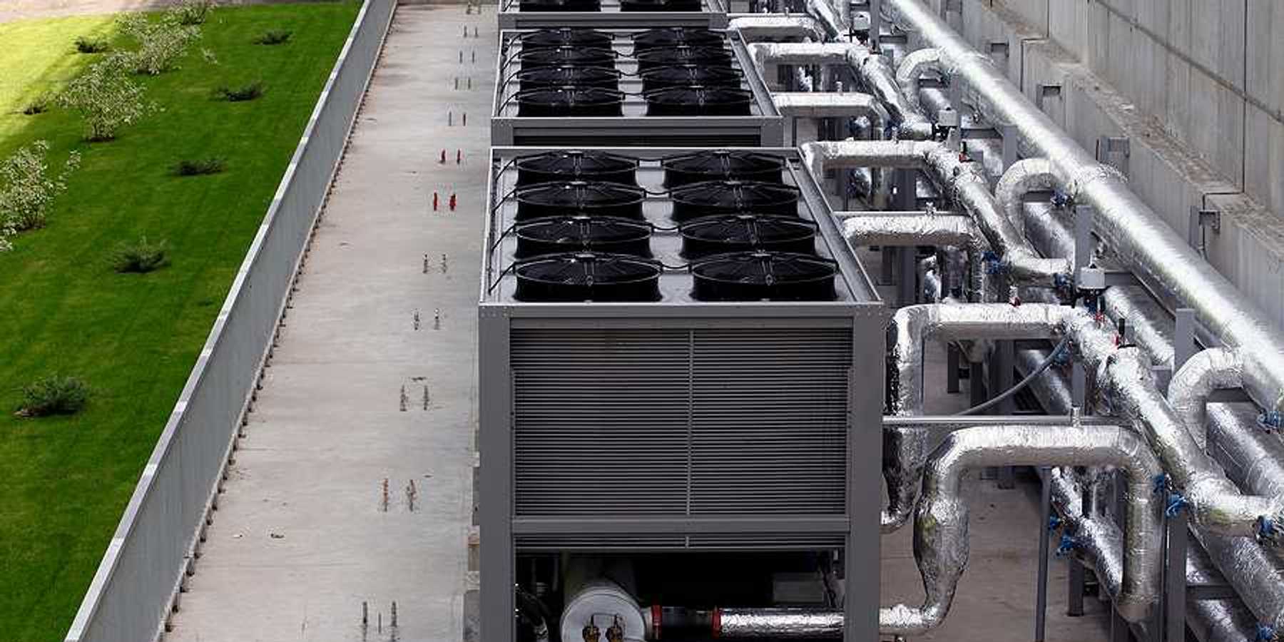 A row of data center cooling towers connected to a building with pipes