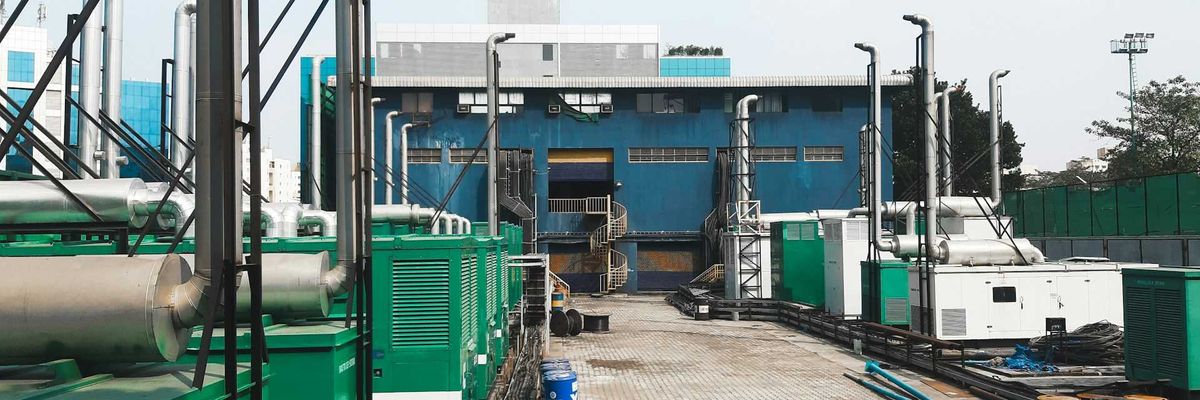 A row of diesel-powered generators outside of an industrial building