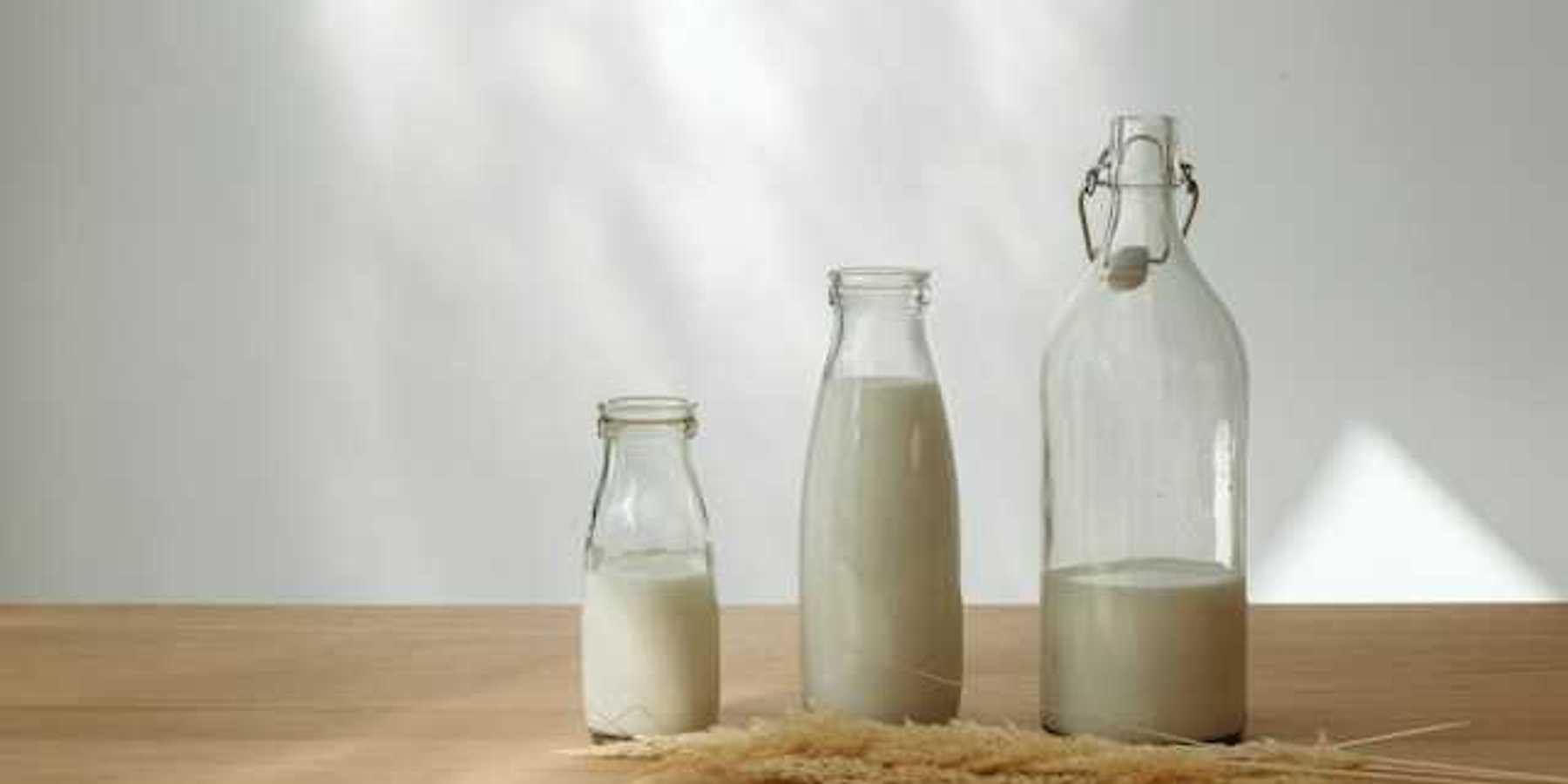 A row of glass jars with milk in them, with a sheaf of wheat in front of them