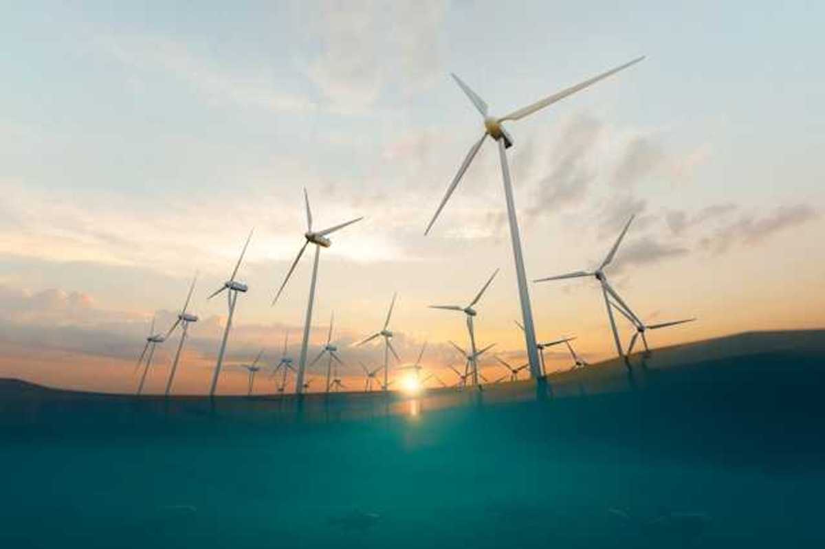 A row of offshore wind turbines with the setting sun in the background