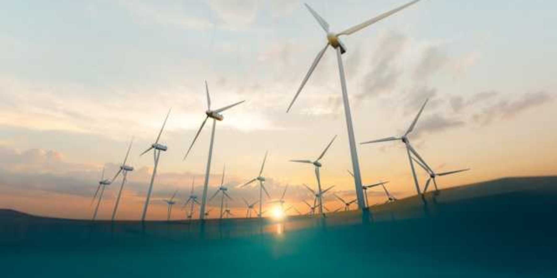 A row of offshore wind turbines with the setting sun in the background
