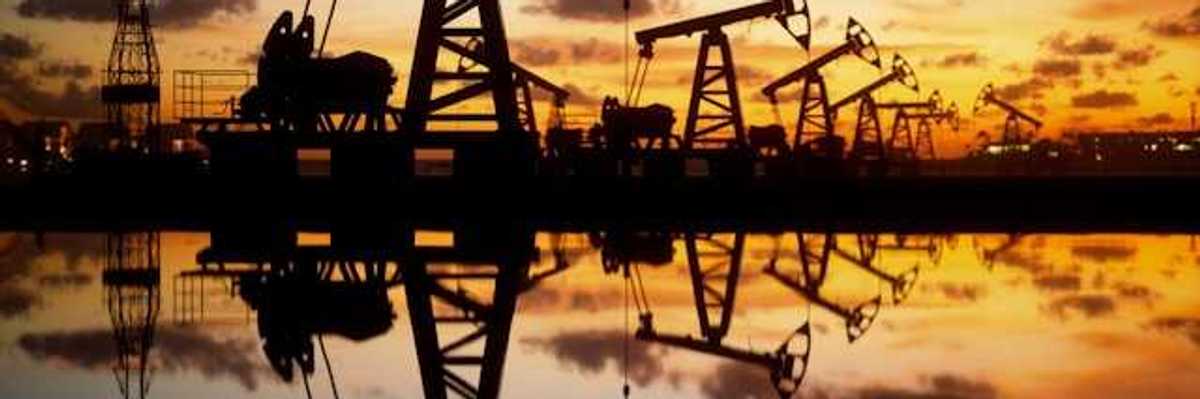 A row of oil drilling pump jacks against a sunset