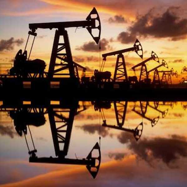 A row of oil drilling pump jacks against a sunset
