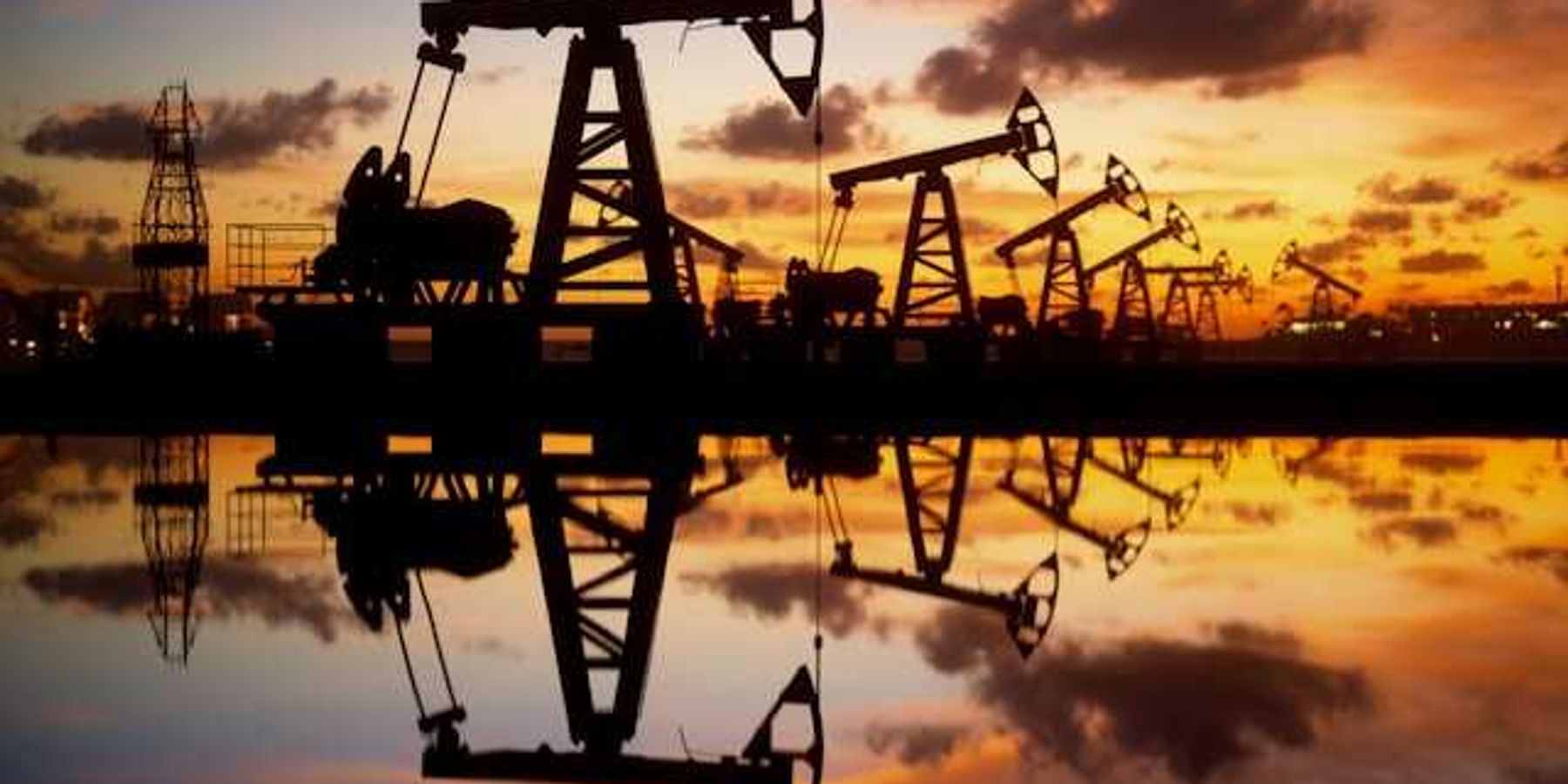 A row of oil pump jacks at sunset