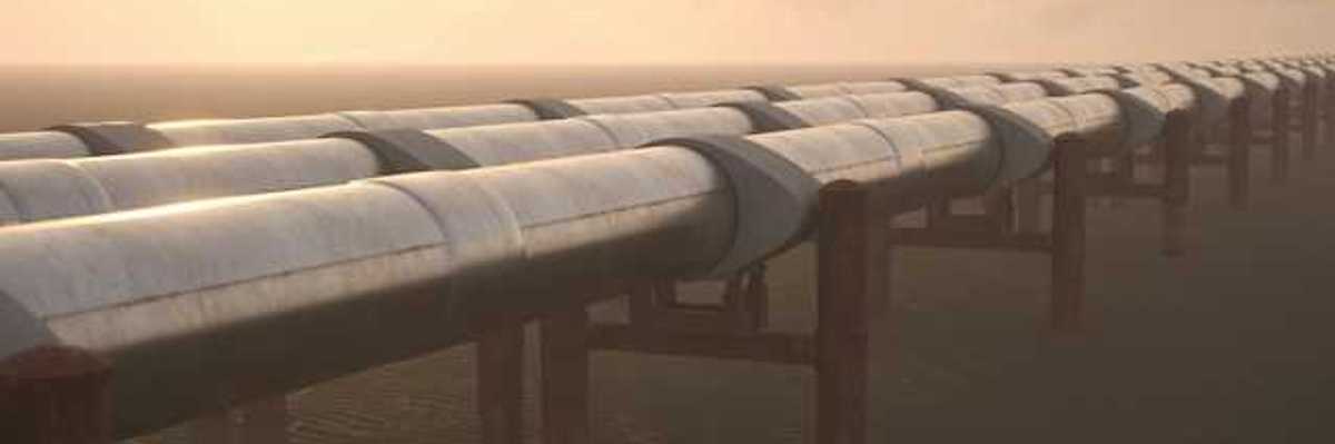 A row of pipelines stretching across a dry environment with mountains in the background